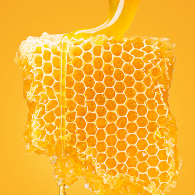 Sweet honeycomb with honey on yellow studio background